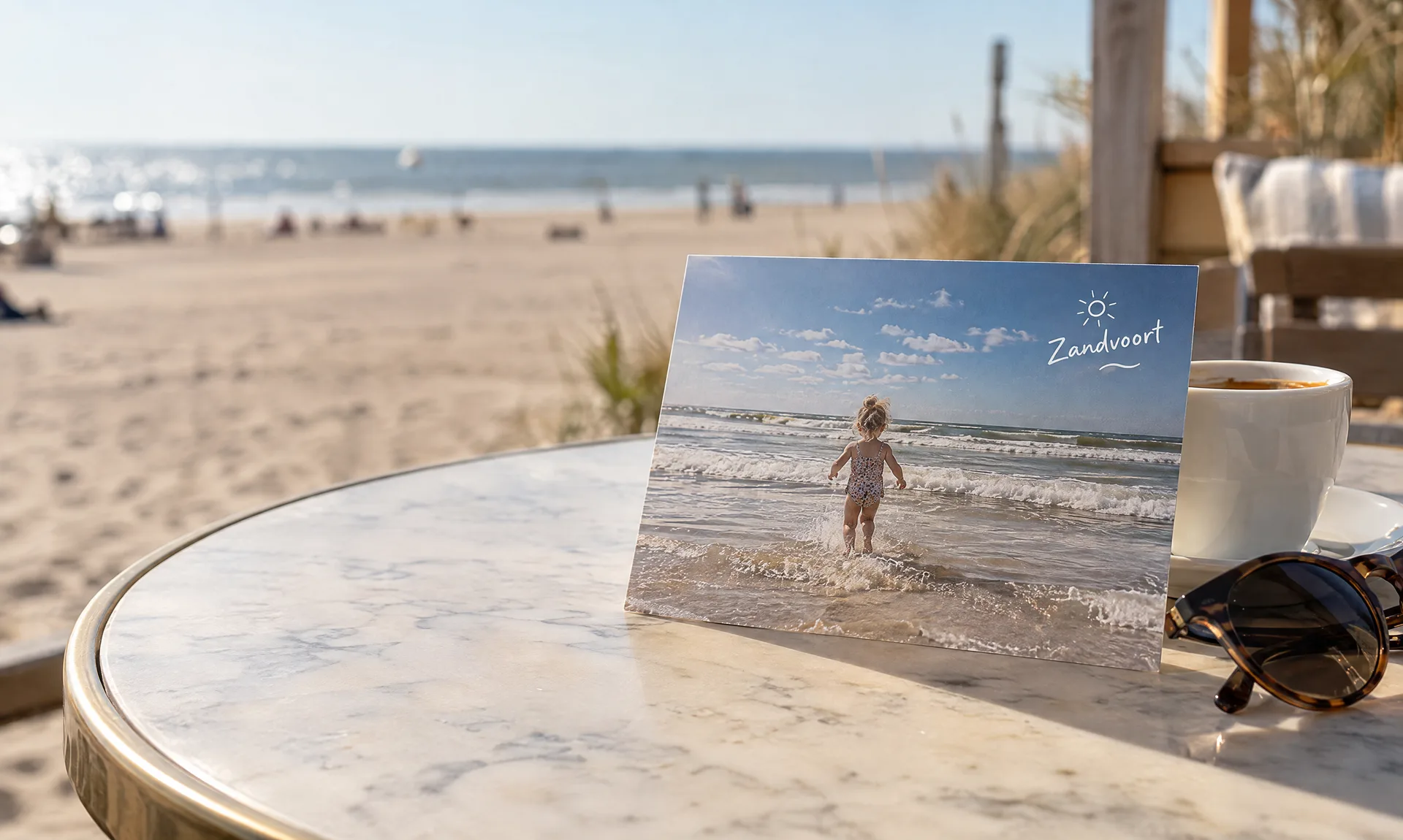 Eine Postkarte an einer Espressotasse auf einem Strandcafétisch: ein Kind, das in Zandvoort ins Meer rennt